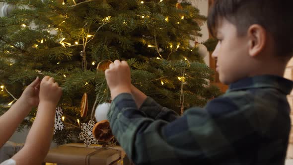 Sibling decorating Christmas tree together. Shot with RED helium camera in 8K