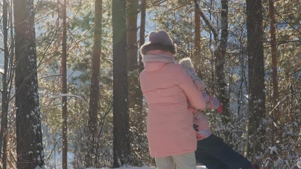 Woman with Child Having Fun in Winter Pine Forest