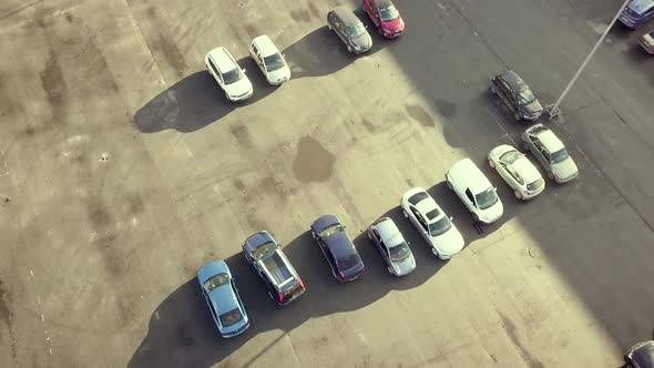 Top aerial view of many cars on a parking lot of supermarket or on sale car dealer market.