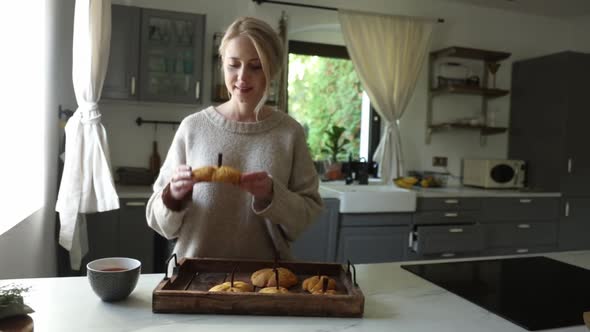 Woman eating pumpkin cookies at kitchen