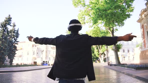 Young Stylish Hipster Black Man in White Headphones and Sun Glasses Dancing Outdoor in City Centre