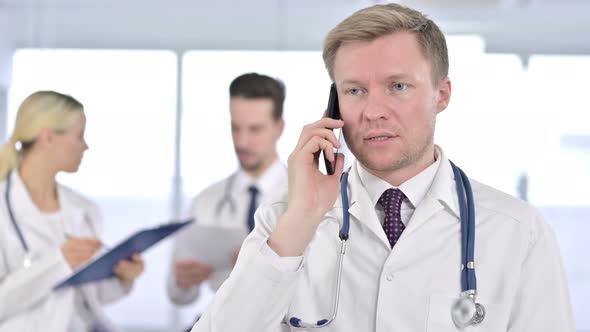 Portrait of Focused Male Doctor Talking on Smartphone