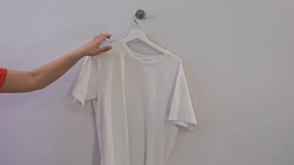 Woman Holding Hanger with Blank Tshirt and Blue Jeans on White Background