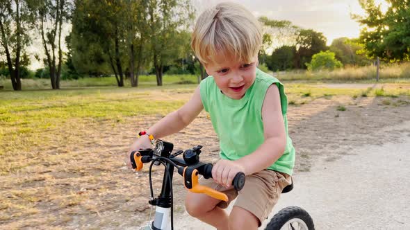 Close Shoot of a Handsome Blond Boy Ride Bicycle in Park
