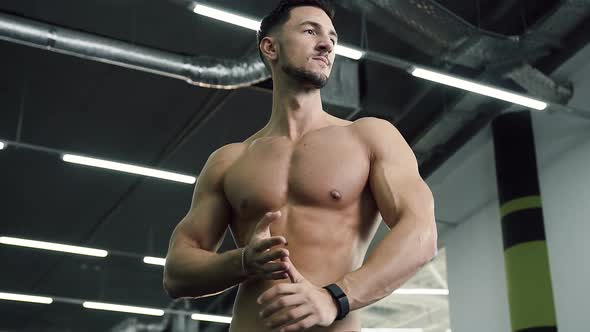 Attractive Young Man Without t-shirt Rub His hands on the Gym Background