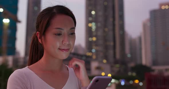 Woman use of mobile phone in city at sunset time