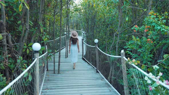 Woman walking in the middle of an ecotourism hotel in the tropical jungle seen from behind