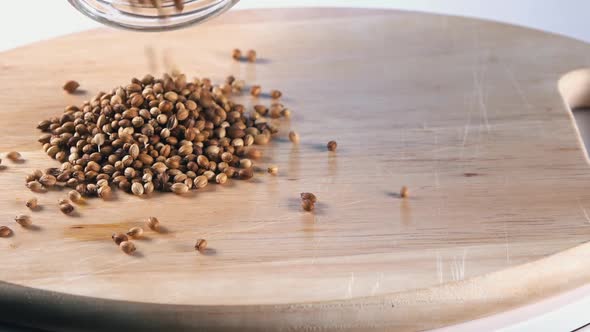 Slow Motion Shot of Coriander Seeds Being Poured on to a Wooden Board