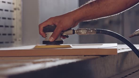 Slow motion of a worker polishing a cabinet door in a furniture factory