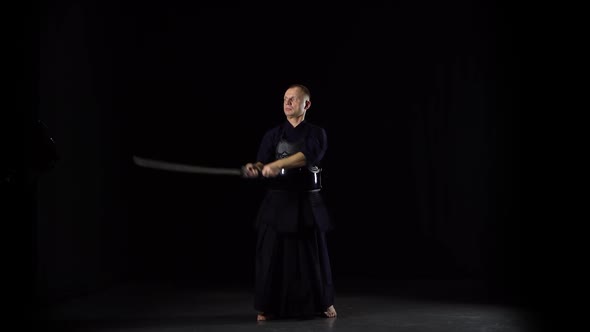 Kendo Warrior Practicing Martial Art with the Katana Sword on Black Background