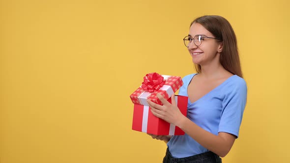 Overjoyed Young Blonde Woman Opening Festive Red Package Bow Celebrating Seasonal Holiday Isolated