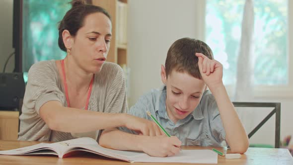 Mother helping her son to do his homework at home