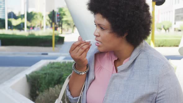 Plus size biracial woman eating salad in city