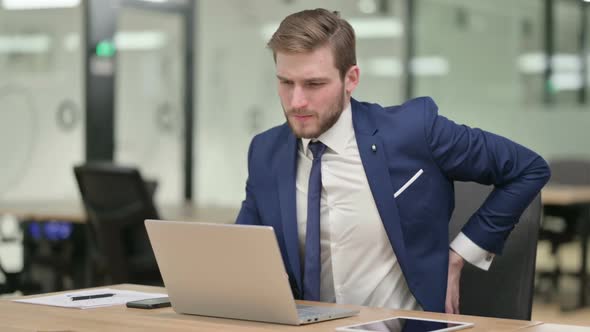 Young Businessman Having Back Pain While Working on Laptop