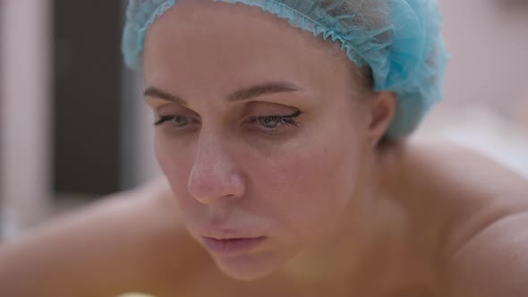 Closeup Portrait of Beautiful Concentrated Woman in Shower Hat Lying in Beauty Spa Waiting