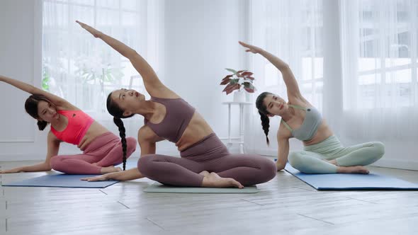 Asian female yoga teacher is teaching students in class basic exercises