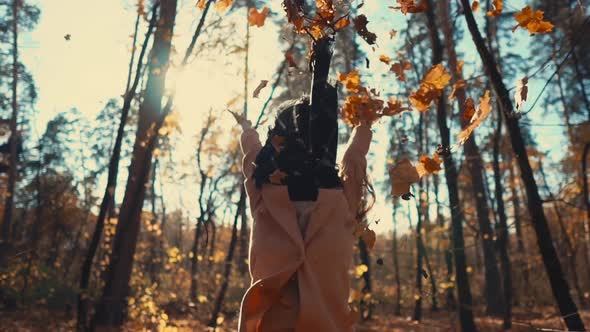 Happy Young Woman Is Tossing Leaves Up and Whirling Joyfully in Autumn Woodland