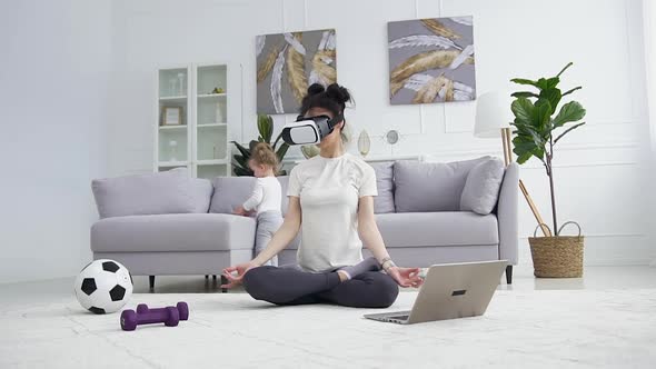 Young Brunette in Special 3d Glasses Meditating on the Carpet while Her Beautiful Small Daughter