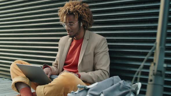 Afro Man Sitting on Street and Video Calling on Laptop