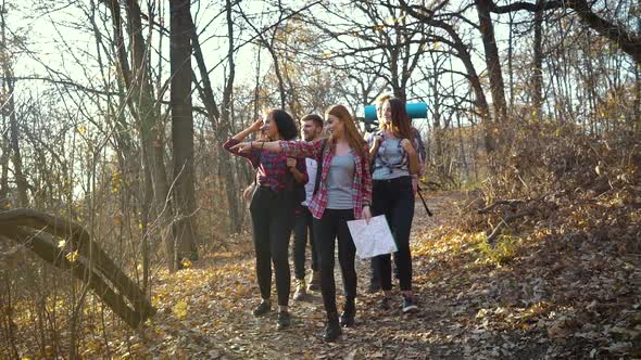 Group of hikers walking in autumn forest with paper map