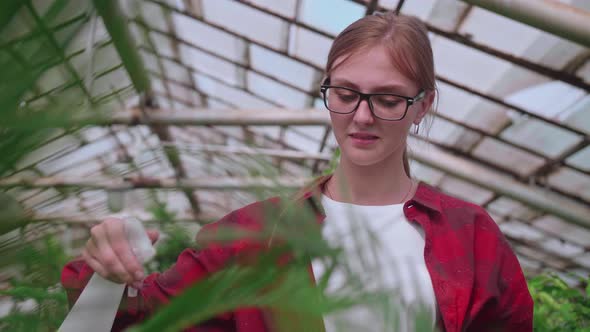 Girl with Glasses Sprays Plants From a Splash or Spray