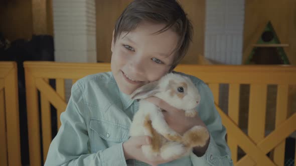 Boy Holds a Rabbit in His Hands on a Farm.