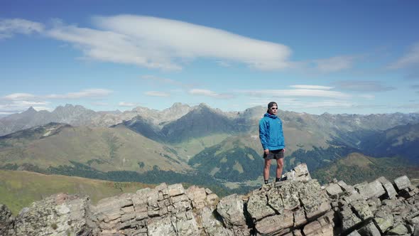 Aerial view, drone moving around a young man on the mountain