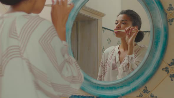 Close Up of 20s African American Woman Brushing Her Teeth in Blue Bathroom