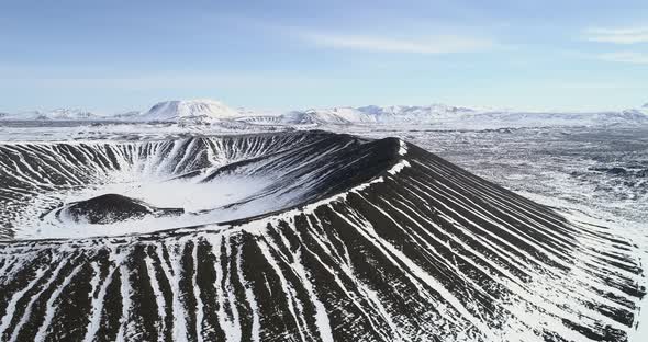 aerial of the Hverfjall volcano in Iceland and surrounding mountains covered in snow