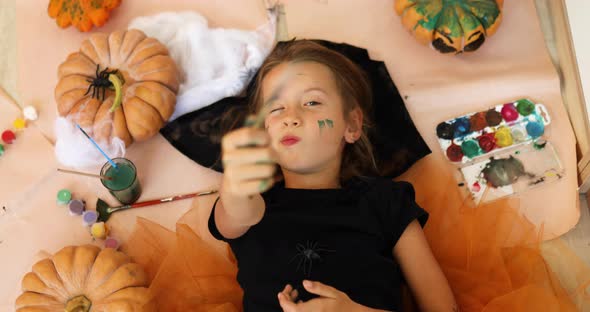 Top view of Smiling girl lying on the floor between drew pumpkin Halloween