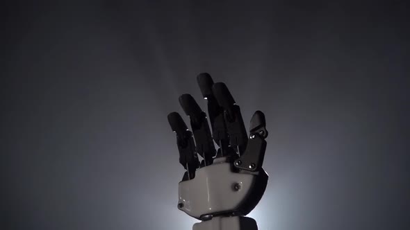 Robot Hand Close Up Waving Goodbye. Black Background. Close Up. Slow Motion