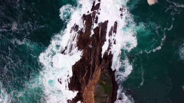 Blue Ocean Waves Crash onto Sharp Rocks, Rising Ultra Wide Drone Shot