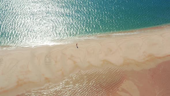 Aerial View of a Tourist Running Along Isolated Coastline