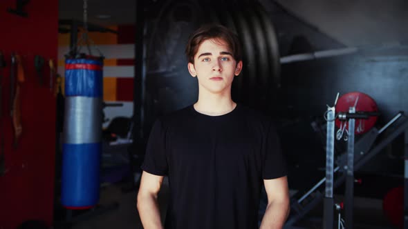 Young Athlete in the Gym Shows His Strong Hands in Front of the Camera