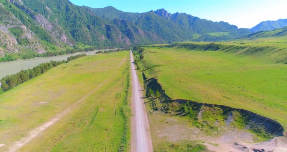 Aerial Rural Mountain Road and Meadow at Sunny Summer Morning. Asphalt Highway and River.