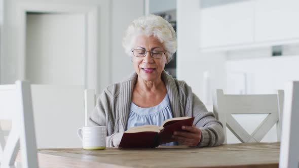 African american senior woman reading a book while sitting at home