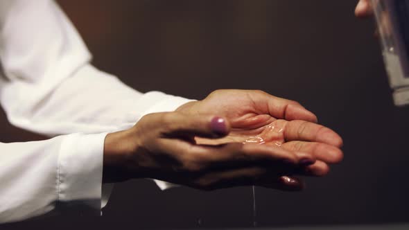 Woman sanitizing her hands with gel - close up isolated