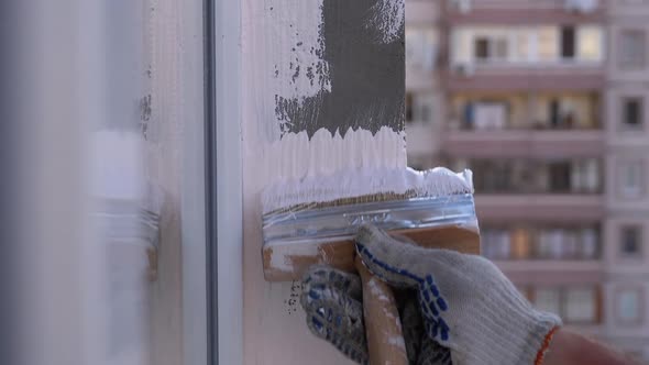 Industrial Climber Paints Wall of Facade with White Paint Using Paintbrush. Slow Motion