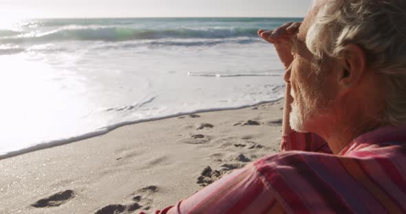 Senior man sitting looking away at the beach