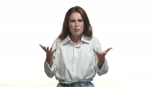 Studio Shot of Attractive Young Woman in Shirt Frowning Looking Confused and Shocked Asking What and