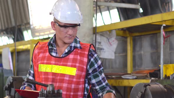 Engineer foreman with repair checklist working repair on machine at the factory