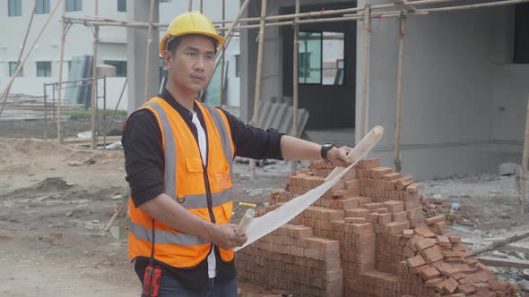 Architect or engineer man wearing hardhat looking blueprint for inspect and planning construction.