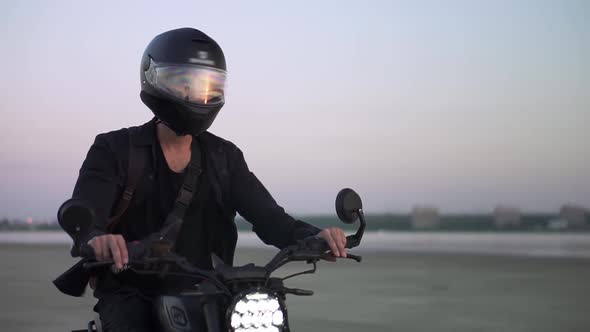 Concentrated Biker Rides on Black Sport Bike in Helmet with Switched Front Headlight