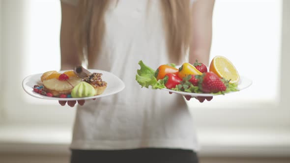 A Sporty Woman is Making Choice Between Fresh Fruits and Crisps