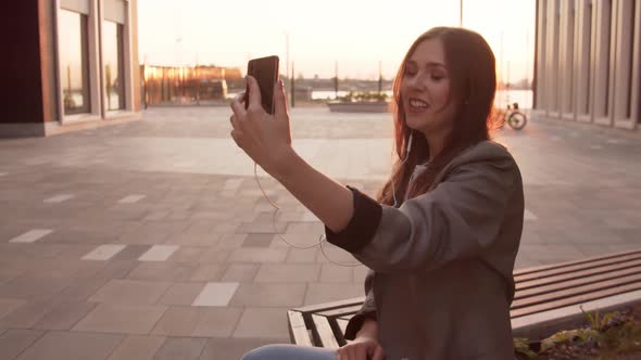 Young attractive business woman sitting outdoor on the bench and using smartphone.