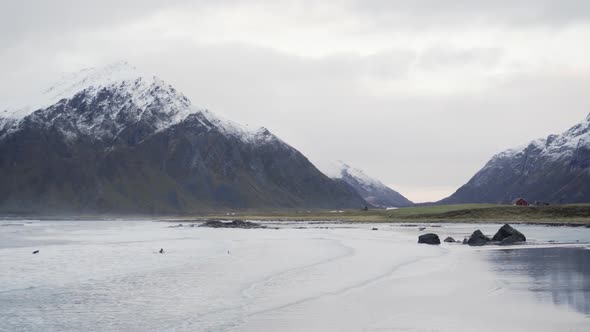 Surfers In Sea Under Snow Capped Mountain