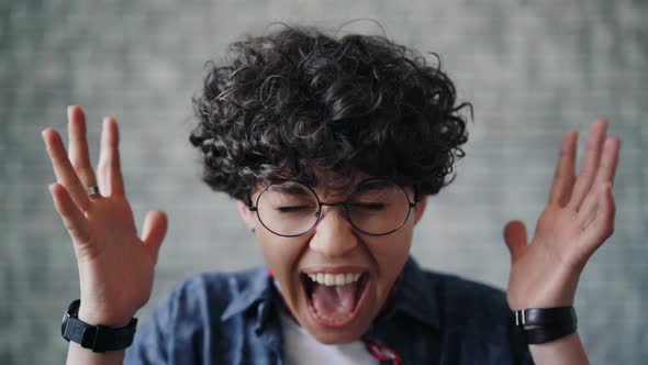 Close-up Portrait of Beautiful Woman Screaming Against Brick Background