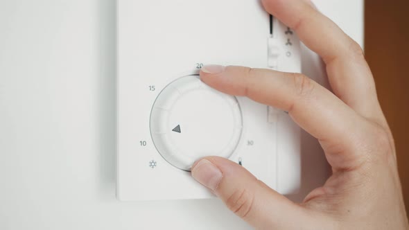 Hand Setting Up the Temperature Using a Smart Thermostat Climate Control on a White Wall in Hotel