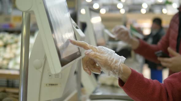 Customer in Plastic Gloves Presses Finger on Touch Screen of Electronic Balance in Supermarket