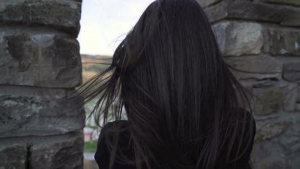 Brunette Girl Watching Trough Medieval Stronghold Wall and Taking Pictures with Smartphone